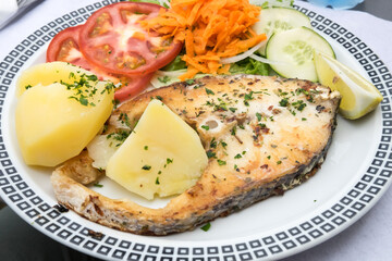 Traditional seafood dish from Madeira island cuisine is a variation of famous fish and chips - oily grilled swordfish fillet served with boiled potatoes and fresh vegetables