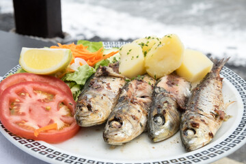 Traditional seafood dish from Madeira island cuisine - oily grilled sardines served with boiled potatoes and fresh vegetables
