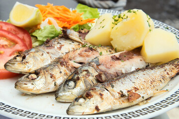 Traditional seafood dish from Madeira island cuisine - oily grilled sardines served with boiled potatoes and fresh vegetables
