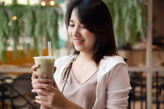 happy young asian woman drinking boba milk tea, bubble milk tea, pearl milk tea