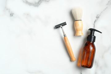 Eco-friendly shaving accessories and amber glass bottle with lotion on marble background. Flat lay, top view.
