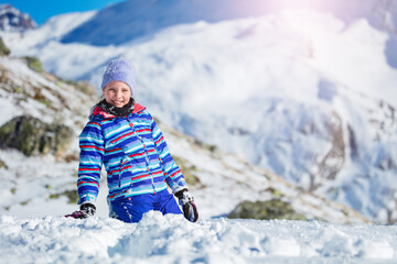 Fototapeta na wymiar Happy girl's with big smile portrait sit in the snow during walk in the mountain in winter clothes