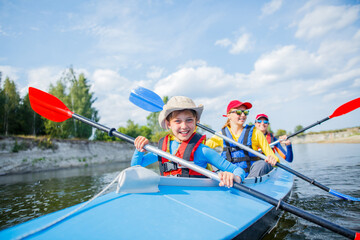 Happy boy kayaking on the river on a sunny day during summer vacation - 361337339