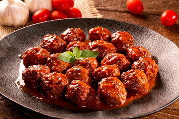 Traditional spicy meatballs in tomato sauce on wooden background. Selective focus.