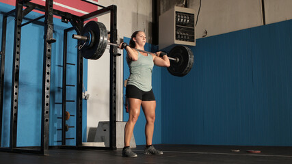 Young pretty female weight lifter lifting heavy weights.