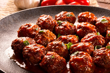 Traditional spicy meatballs in tomato sauce on wooden background. Selective focus.