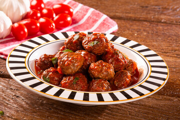 Traditional spicy meatballs in tomato sauce on wooden background. Selective focus.