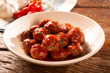 Traditional spicy meatballs in tomato sauce on wooden background. Selective focus.