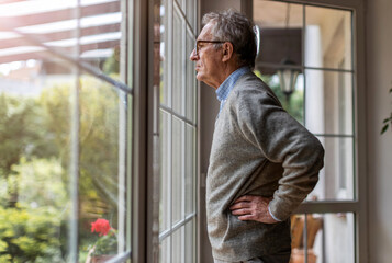 Obraz na płótnie Canvas Senior man looking out of window at home 