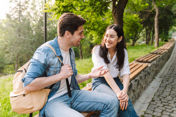 Image of couple talking and smiling at each other while sitting on bench