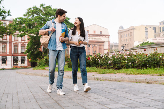 Image of couple talking and drinking coffee takeaway while walking