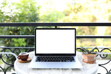 Laptop with coffee cup and plant pot on metal table at corridor
