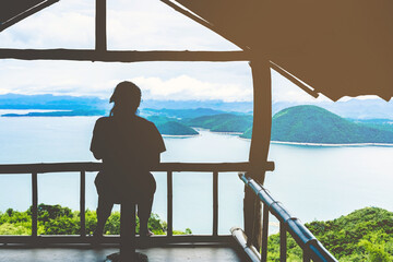 Back view of woman enjoy with beautiful scenery view of nature with a large reservoir above the Srinagarind Dam at Rai Ya Yam view point in Si Sawat District, Kanchanaburi Thailand.