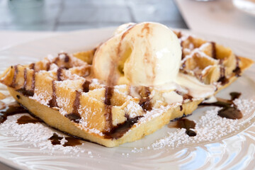 Traditional Belgian homemade waffles with sweet chocolate sauce and a cup of vanilla ice cream served at the confectionery of Funchal, Madeira island
