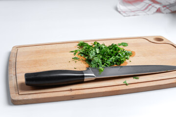 Sliced parsley on a wooden Board next to a knife in the kitchen