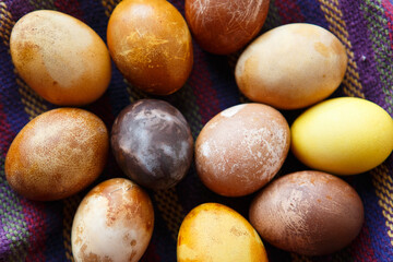 filled frame background wallpaper shot of a bunch of original colorful dragon or dinosaur looking like chicken Easter eggs, dyed with natural products (red wine, tea, coffee, carrots, turmeric)