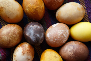 filled frame background wallpaper shot of a bunch of original colorful dragon or dinosaur looking like chicken Easter eggs, dyed with natural products (red wine, tea, coffee, carrots, turmeric)