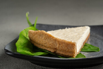 Vegetarian cheesecake on a gray plate with green leaves