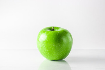 Green apple on a white background. An apple stands on a glass surface.