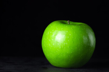 Green apple on a black background. One green apple in the frame