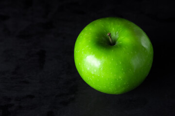 Green apple on a black background. One green apple in the frame