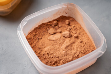 A storage container with carob powder on a gray concrete surface in the kitchen