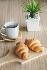 Two fresh croissants and cup of coffee on dark stone table