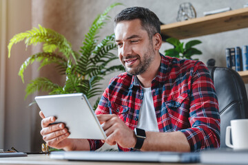 Portrait of middle aged man using tablet at home