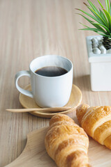 Obraz na płótnie Canvas Two fresh croissants and cup of coffee on dark stone table