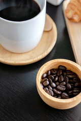 A Coffee background, copy space. White cup of coffee and, coffee beans on dark wooden background