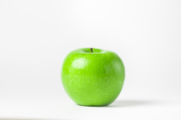 Green apple on a white background. One green apple stands in the middle of the frame