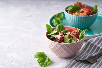 Summer salad of fresh with basil vegetables served in a bowl. A tomato. cucumbers, onions, radishes. sesame seeds and pumpkin seeds Copy space
