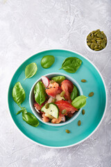 Summer salad of fresh with basil vegetables served in a bowl. A tomato. cucumbers, onions, radishes. sesame seeds and pumpkin seeds Copy space
