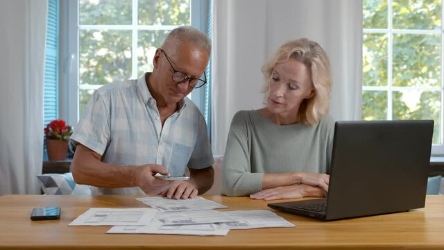 Senior couple scan qr-code to pay bill online at home