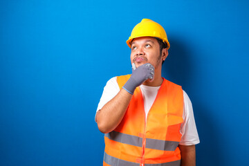 Asian workers wearing helmets are seen looking for ideas in completing work against blue background