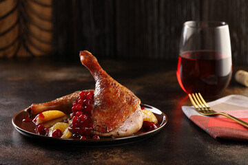 Roasted duck legs with red cranberry sauce and orange slices, served with red wine. Tasty and healthy food.