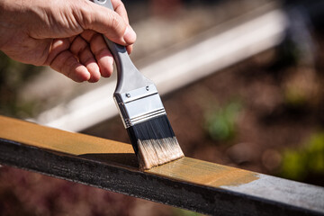 man is painting a metal railing with copper varnish