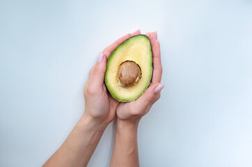 Close up woman's arm with a half of ripe fresh avocado isolated on white