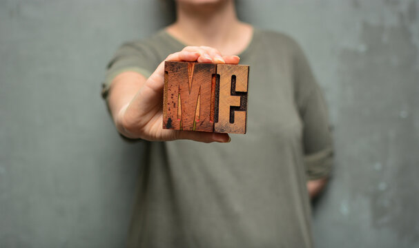 Woman holding the word "me" made of wooden typographic letters. Emancipation, personality, human rights, LGBT, feminism, self-confidence, healthy self-assertion concept
