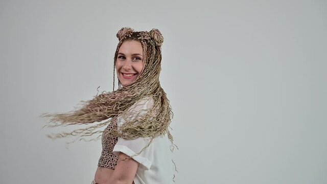 Caucasian happy woman with dreadlocks moves in the studio. Video shot on a white background.