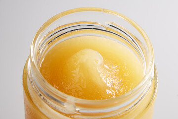 Beautiful macro image of honey in a jar from above. Appetizing golden drop of honey with a textured texture.