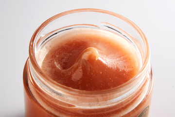 Beautiful macro image of honey in a jar from above. Appetizing golden drop of honey with a textured texture.