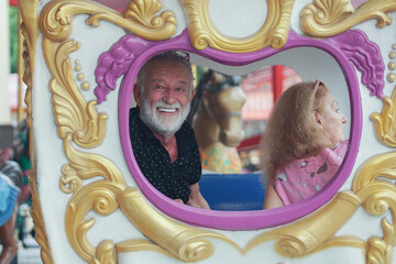Caucasian Senior couples smile on merry go round at the amusement park
