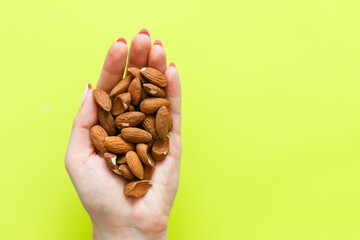 image of hands holding hazelnuts over light green background