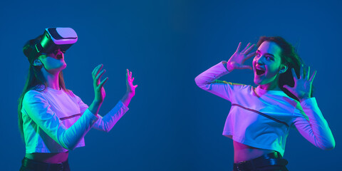 Astonished, playing. Caucasian young woman's portrait on blue studio background in neon. Beautiful female model in casual. Concept of human emotions, facial expression, sales, ad. Flyer with copyspace