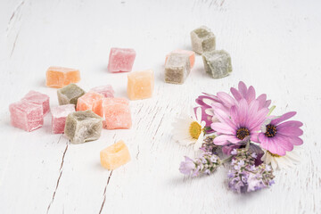 Turkish delights and spring flowers on a table with copy space