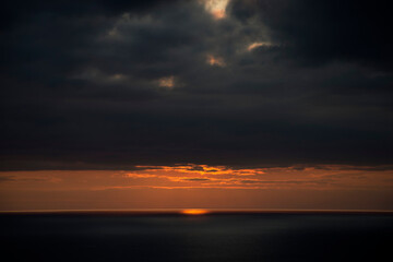 Fototapeta na wymiar The sun sets behind the waves round the northern irish causeway coast