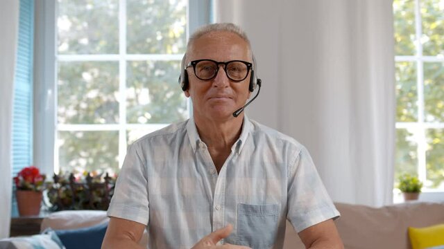 Mature man with headset having video conference at home office