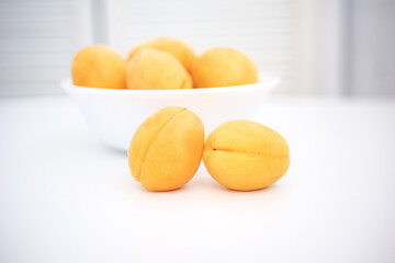 Apricot on a wooden white background. Sliced apricot, apricots in a plate, apricot slices