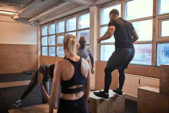 Diverse group of people doing box jumps during a workout